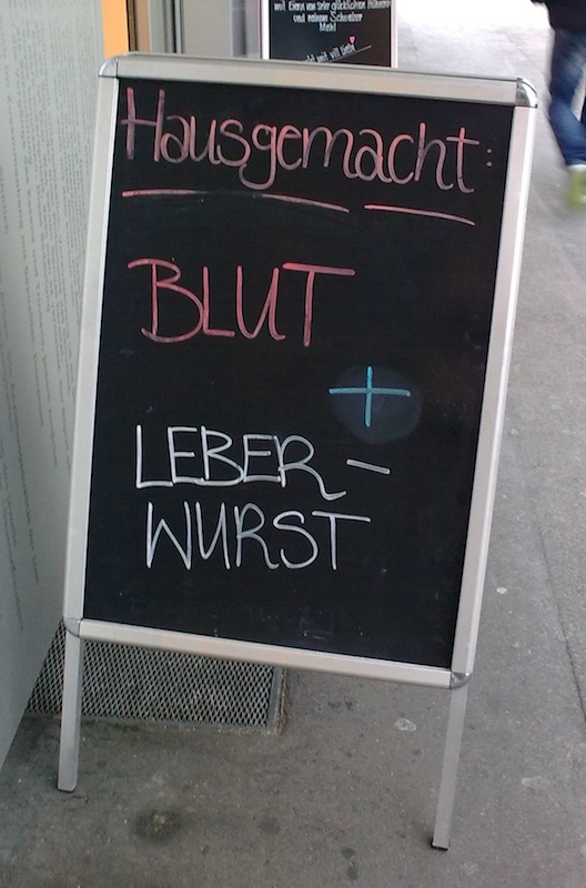 Werbeschild vor der Metzgerei: "Blut + Leberwurst"